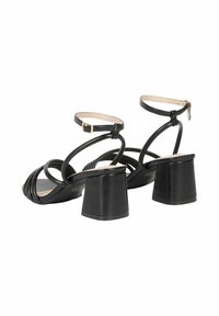 Sandali neri con tacco a blocco spesso, punta aperta e sottili cinghie alla caviglia. Presentano un design incrociato nella parte anteriore.