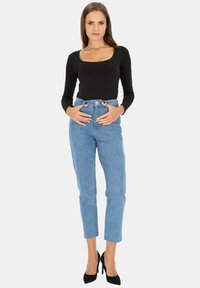 Czarny długi rękaw top z kwadratowym dekoltem, w połączeniu z jasnoniebieskimi spodniami z wysokim stanem i czarnymi szpilkami. Prosty krój, dopasowana sylwetka.