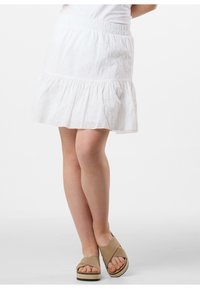 Hvid bomuldsnederdel med et lagdelt flæse-design, der har hulmønsterdetaljer. Elastisk talje og bæres med beige espadrillesandaler.