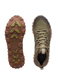 Zapatos de senderismo verdes y marrones con una parte superior de tela texturizada, puntera de goma y una suela robusta que presenta un patrón de camuflaje y grandes tacos de tracción.