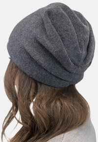 Grå strikket hue med en slouchy design, tekstureret stof og lagdelte folder bagpå, velegnet til koldt vejr.