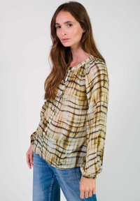 Langueshirt, met knopen in doorschijnende stof met een beige en bruine ruitpatroon. Heeft gathered manchetten en een ronde halslijn.