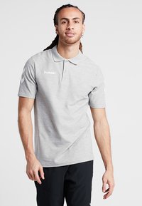 Grå polo-shirt med en blød tekstur, der har en krave, tre knapper og hvid "hummel" branding på brystet og ærmerne.