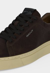 Baskets en daim marron avec lacets noirs, semelle en caoutchouc beige et logo "GANT" sur le côté et la languette.