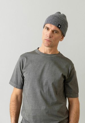 Grå ribbet strikket hue med et lille logo-tag. Grå crew-neck t-shirt med korte ærmer, glat tekstur, tætsiddende design.