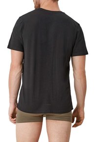 Black cotton t-shirt with a crew neck, short sleeves, and a smooth texture, worn over khaki briefs, viewed from the back.