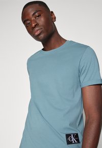 Calvin Klein Jeans BADGE TURN UP SLEEVE - T-shirts - goblin blue