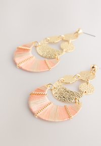 Gold and peach hoop earrings featuring textured metal discs and a fringe design, with alternating smooth and textured finishes.