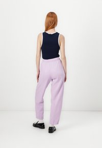 Navy sleeveless top with white trim, paired with lilac elastic-waist pants. The pants have a loose fit and are worn with black shoes.