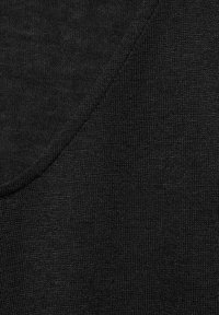 Schwarzer Strickstoff, der eine strukturierte Oberfläche zeigt, mit einem sanften Übergang zwischen zwei Abschnitten, der die Dichte und das Gewebe des Stoffes hervorhebt.