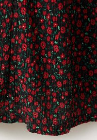 Tissu noir avec de petites fleurs rouges et des feuilles vertes formant un motif floral dense, avec un bord froncé et élastiqué en bas.