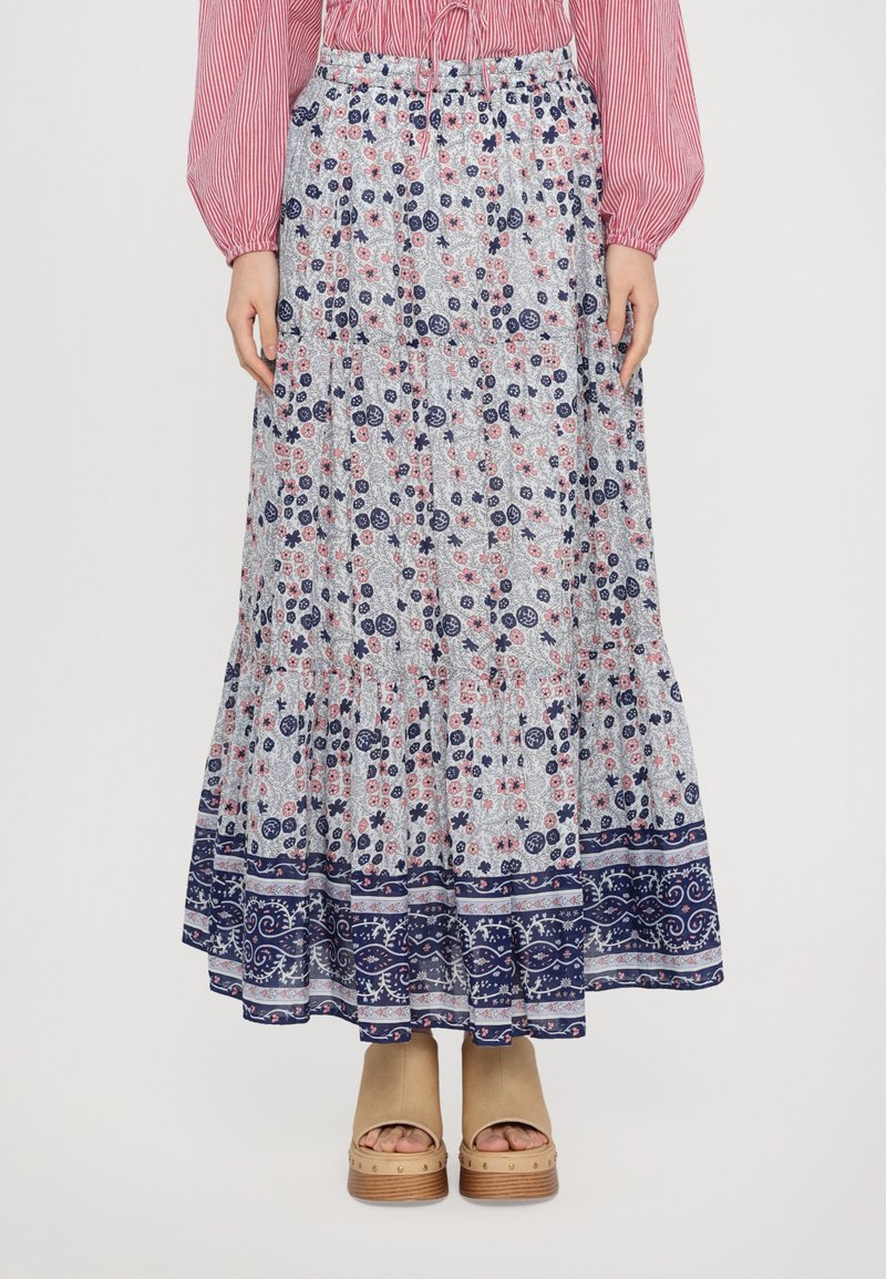 Floral Maxi-Rock in Hellblau mit roten und marineblauen Mustern, mit gestuftem Rüschendesign, elastischem Taillenbund, kombiniert mit tanfarbenen Plateau-Sandalen.