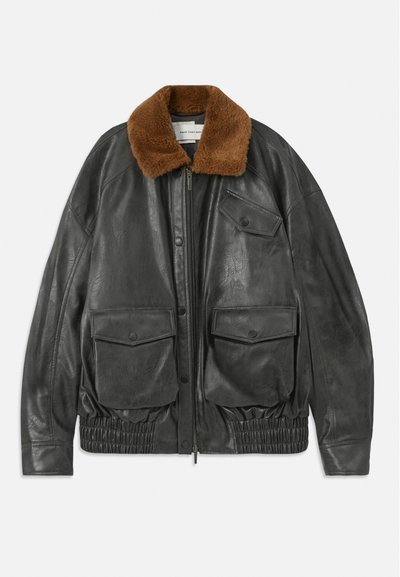 Black leather jacket with a brown faux fur collar, zip closure, elasticated hem, and two front patch pockets. Smooth texture and relaxed fit.