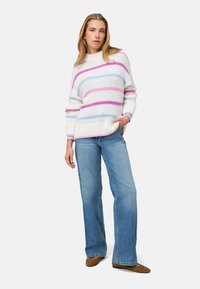 Pull en maille blanc avec des rayures horizontales roses et bleues, associé à un jean évasé bleu clair et des ballerines marron. Design simple et décontracté.