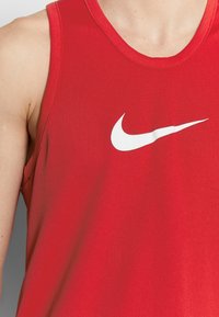 Débardeur de sport rouge en tissu respirant, avec un logo Nike blanc sur la poitrine et un col rond.