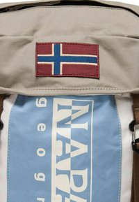 Hellgrauer Rucksack mit einem gestickten norwegischen Flaggenpatch in Bordeauxrot und Blau. Beinhaltet hellblaue und weiße Markenstoffe mit auffälligem Text.