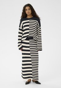 Lenta adīta džemperis un svārki jūras zila un krēmkrāsā, ar pārmaiņus blokiem, ribotu tekstūru un brīvu piegriezumu.