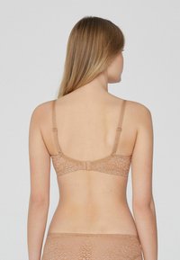 Podprsenka s krajkovým zadním dílem v tělové barvě se nastavitelnými ramínky a zapínáním na háček. Obsahuje květinové vzory po celé látce.