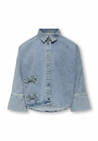 Světle modrá džínová košile s límečkem, patkovými knoflíky a dvěma mašličkami na levé straně. Má široké rukávy a lehce zkrácený spodní lem.