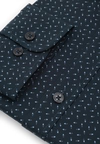 Ciemnoniebieska koszula z długim rękawem w wzory, z małymi jasnoniebieskimi kształtami geometrycznymi oraz czarnymi guzikami z wygrawerowanym napisem "Pako Lorente."