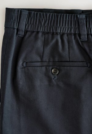 Ciemnoniebieskie spodnie z elastycznym pasem, szlufkami na pasek oraz tylną kieszenią z jednym czarnym guzikiem. Gładki materiał o delikatnym połysku.