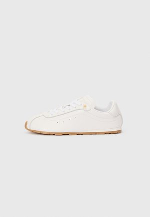 Laags profiel witte leren sneaker met witte veters, klein goudkleurig logo nabij de bovenste oogjes en lichtbruine rubberen zool.