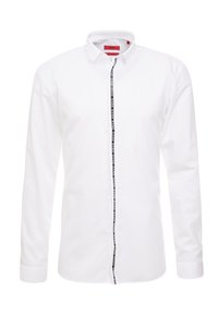 Valkoinen pitkähihaisessa paidassa on napillinen kaulus ja keskellä musta logonauha. Valmistettu sileästä kankaasta, jossa on siistit linjat.