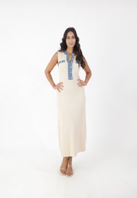 Maxikjole i cremefarvet ribbet stof med en denim brystlomme og knaplukning foran. Har ærmeløs design og to forlommer. Klare strop sandaler.