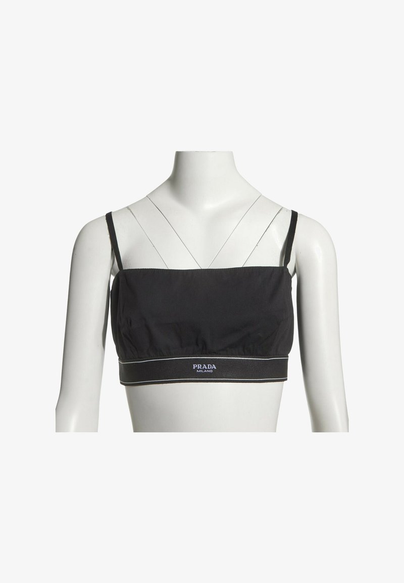 Top court noir Prada avec fines bretelles et logo sur l'ourlet élastique, présenté sur un buste de mannequin blanc.