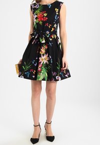 Czarna sukienka w kwiaty z krótkimi rękawami, zdobiona kolorowymi kwiatami i motylami. Dopasowana góra i rozkloszowany dół z wiązanym detalem w talii.