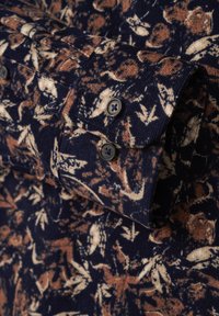 Dunkelblauses Cordhemd mit floralem Muster in Beige und Braun. Verfügt über geknöpfte Manschetten und strukturierte Stoffdetails.