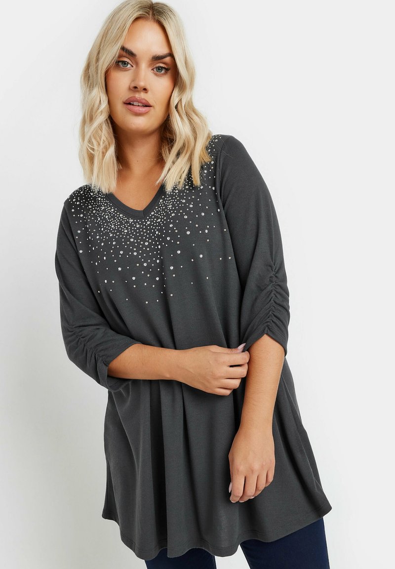 Grijze V-hals top met driekwart mouwen, voorzien van kralendetails en gathers op de mouwen, gemaakt van zachte, lichte stof.