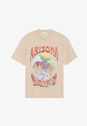 Camiseta gráfica de algodão bege com uma cobra, cactos e paisagem desértica. O texto diz "ARIZONA ESCAPE TO INSPIRE" em rosa e preto em destaque.