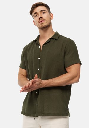 Korte mouwen, olijfgroene button-up shirt van textuurstof, met een kraag en witte knopen, gedragen met lichte broek.