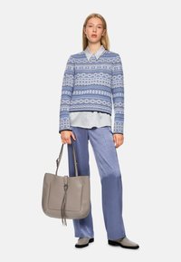 Light blue patterned sweater, light blue shirt underneath, pale blue trousers, gray handbag with tassel detail, and gray ankle boots.