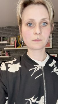 Must mustreid valgete lilledega, millel on lukuga eesmine osa, koos valge särkiga. Isikul on lühikesed juuksed ja erinevad kõrvarõngad.