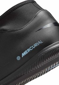 Close-up of black Nike Mercurial sports shoe with textured sole and visible stitching on upper fabric.