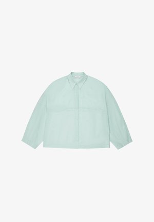 Sobrecamisa grande de manga larga azul claro con cuello puntiagudo y botones frontales ocultos, mostrada extendida sobre un fondo blanco.
