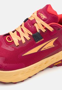 Baskets de sport rouges et jaunes avec un dessus texturé, un laçage proéminent et une semelle rembourrée ; comporte un logo et des accents à motifs.