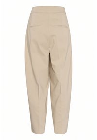 Pantalon beige taille haute et fuselé avec deux poches passepoilées à l'arrière et un détail de couture sur le dos de chaque jambe.