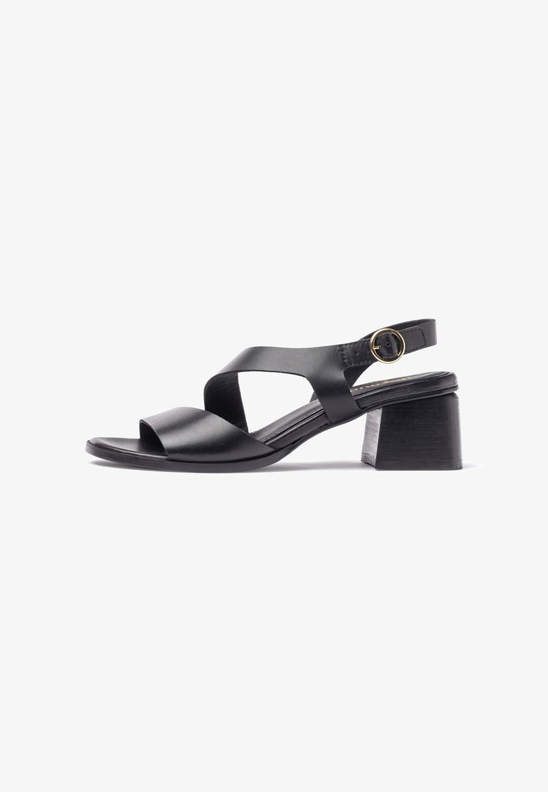 Sandale en cuir noir avec un design à lanières croisées, bout ouvert et talon bloc. Elle dispose d'une bride de cheville ajustable avec une boucle circulaire.