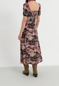 Maxime dress with puff sleeves, colorful abstract pattern in pink, cream, and black, featuring a smocked back and a flowing silhouette.