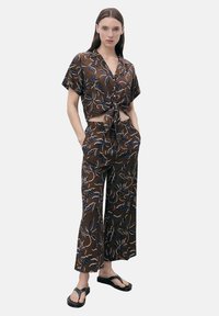 Brown, short-sleeve, cropped shirt with a tie front and matching wide-leg pants. Floral pattern in blue and cream. Black flip-flops.