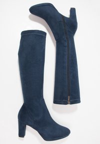 Granatowe, za kolano, sznurowane botki na obcasie z miękkiego, przypominającego zamsz materiału. Posiadają zamek błyskawiczny z boku oraz gładką strukturę z okrągłym noskiem.