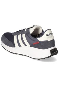 Granatowe sneakersy z białymi paskami, z cholewką z zamszu i siateczki, amortyzowaną podeszwą oraz czerwonym akcentem przy pięcie. Posiadają teksturowaną czarną podeszwę.