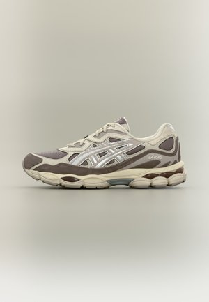 Μπεζ και καφέ παπούτσι της Asics για τρέξιμο με μαξιλαρωμένη σόλα και διχτυωτές επιφάνειες, εμφανίζεται σε προφίλ πάνω σε απλό ανοιχτό φόντο.