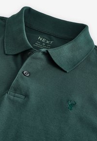 Grøn polo-shirt lavet af struktureret stof, med klassisk krave, tre-knaps knaplukning og et broderet logo på brystet.