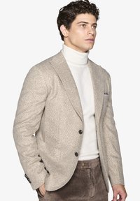 Beige houndstooth blazer med notch lapels, to knapper og skulderpuder, parret med en hvid turtleneck og brune kordfløjl bukser.