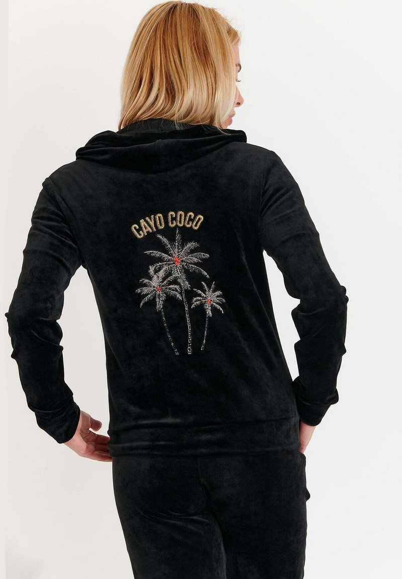 Felpa in velluto nero con la scritta “CAYO COCO” e ricamo di una palma in argento e rosso sulla parte posteriore. Design con cappuccio e maniche lunghe.