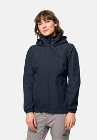 Veste imperméable marine avec capuche, poignets élastiques et fermeture éclair à l'avant. Présente un logo subtil sur la poitrine et une finition lisse.